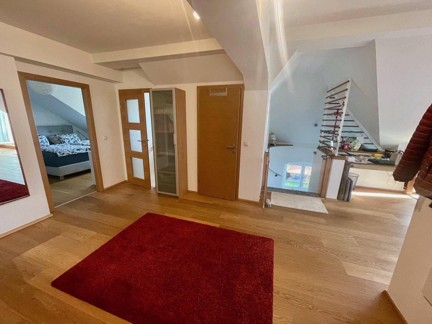 Flur mit Holzboden und Treppe, die in die untere Etage führt, mit Blick auf weitere Räume.