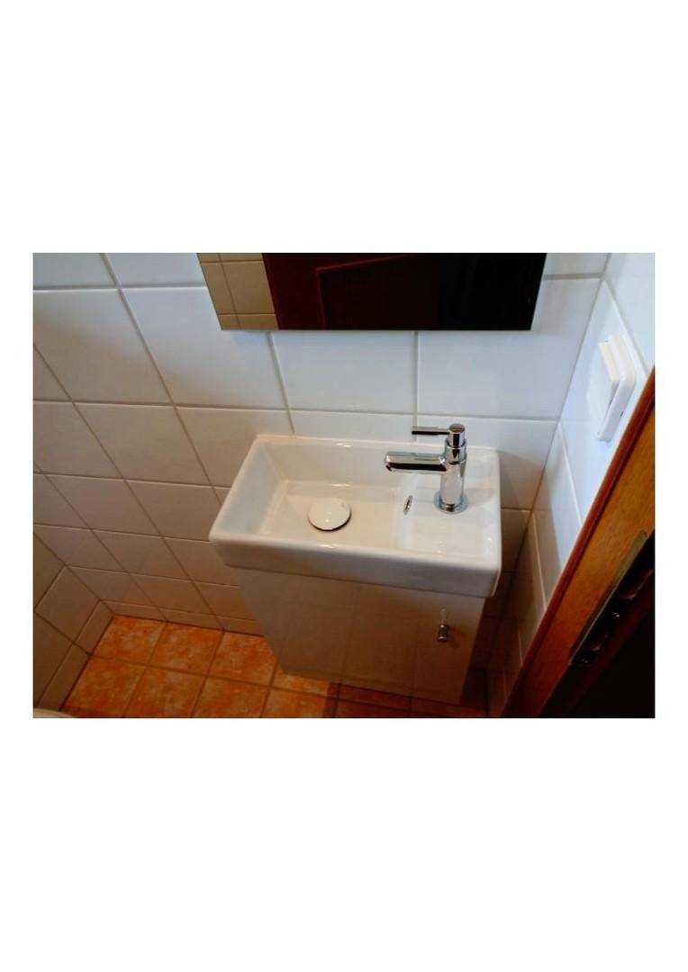 Kleines Gäste-WC mit modernem Waschbecken, Spiegel und weißen Fliesen, praktisch und sauber.