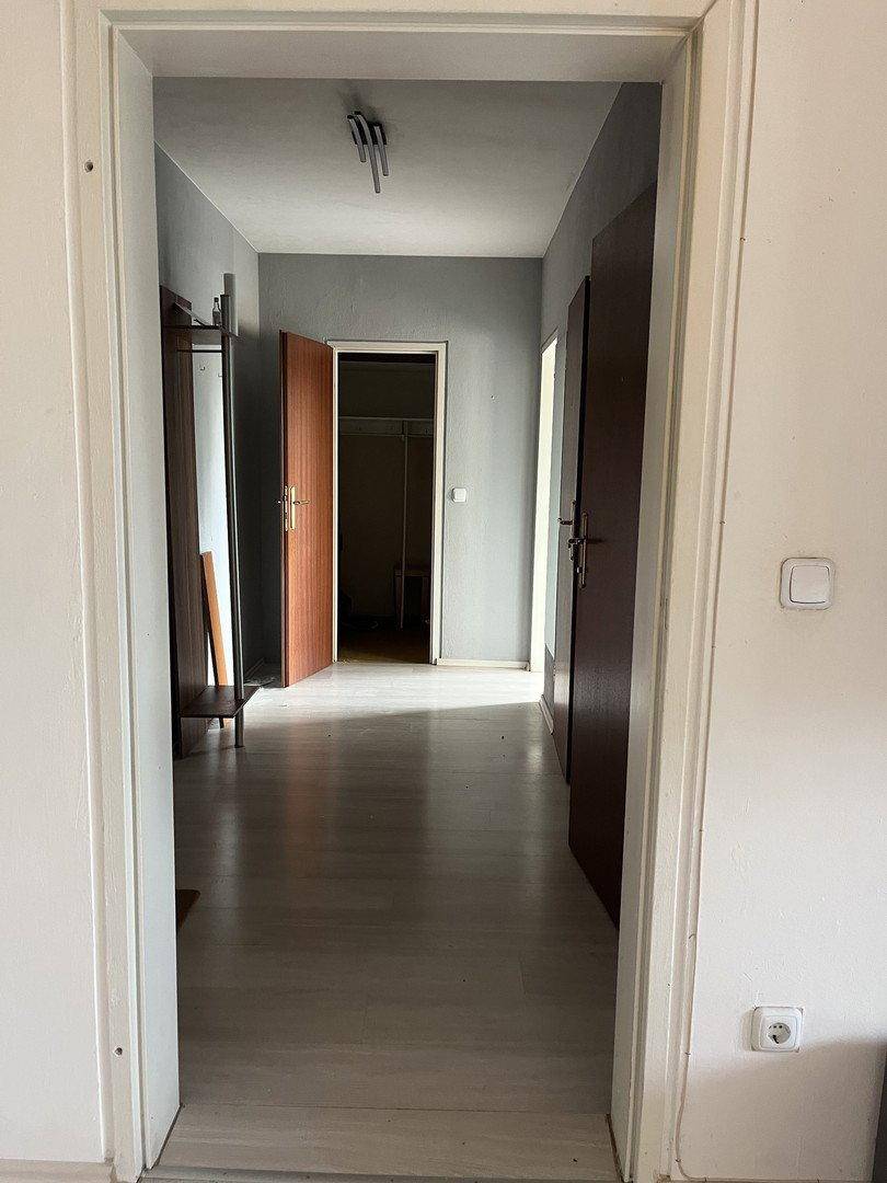 Heller Flur mit Laminatboden und grauen Wänden, der zu verschiedenen Räumen führt.
