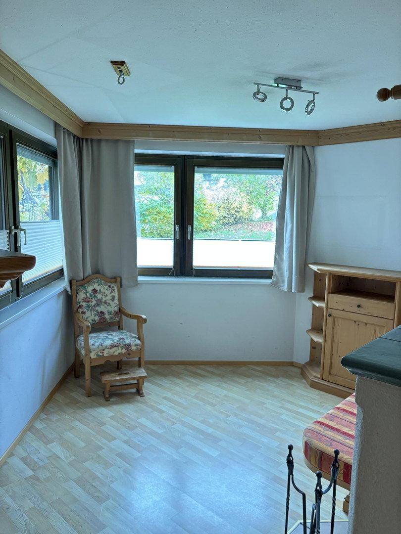 Gemütlicher Raum mit hellem Laminatboden, einem Fenster und traditionellen Holzmöbeln im Landhausstil.