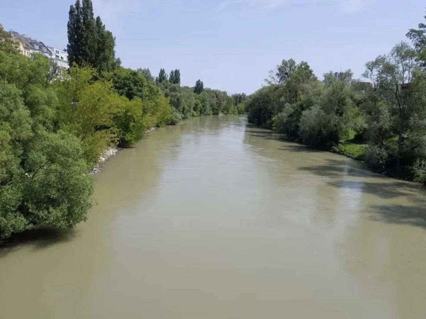 Breiter Fluss umgeben von üppigem Grün und Bäumen unter einem klaren Himmel.
