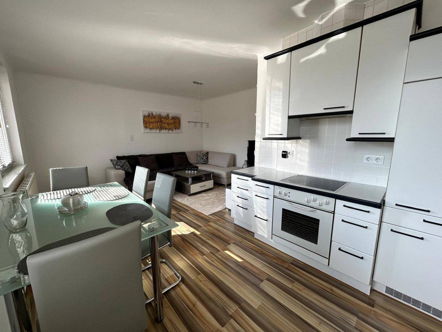 Heller Wohn-Essbereich mit moderner Küche, Esstisch und gemütlicher Sofaecke.