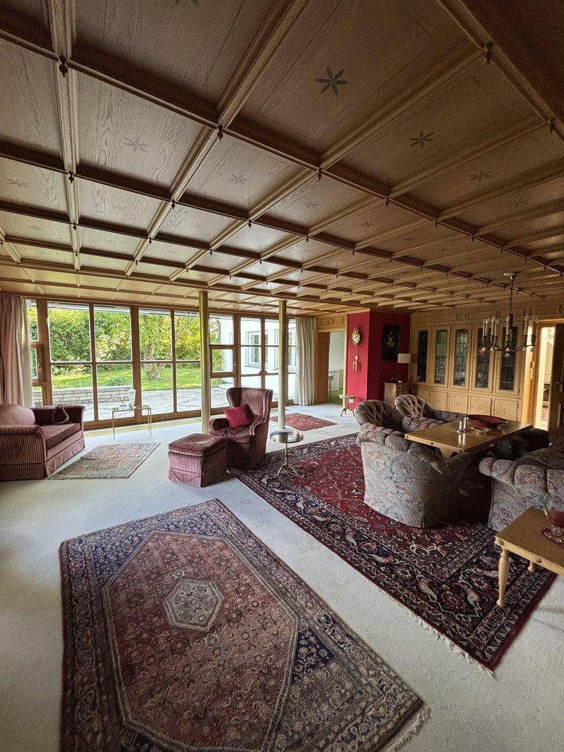 Elegantes Wohnzimmer mit Holzkassettendecke, Teppichboden und traditionellen Möbeln.