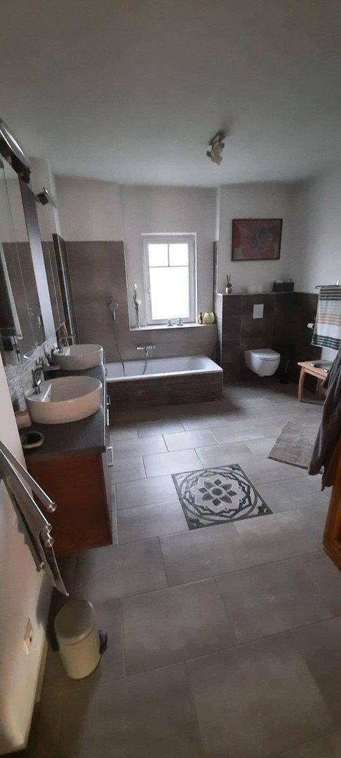 Modernes Badezimmer mit Doppelwaschbecken, Badewanne und grauen Fliesen, bietet Komfort und Funktionalität.