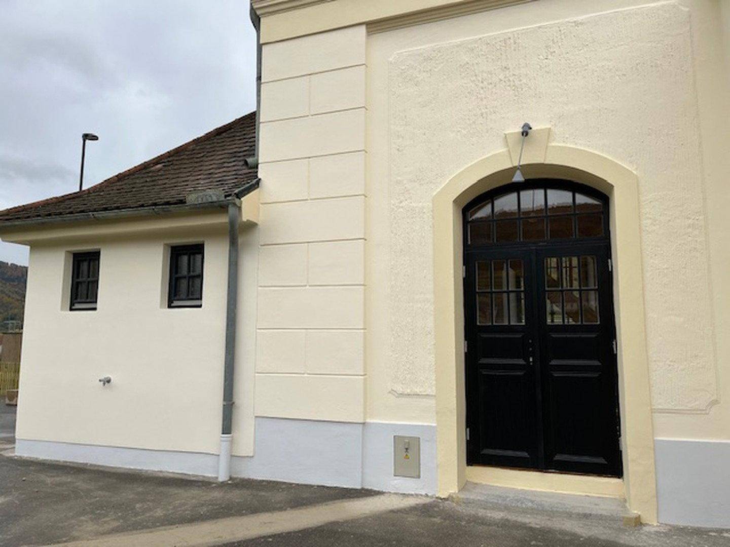 Historische Fassade mit Bogenfenster und schwarzer Doppeltür, frisch renoviert.