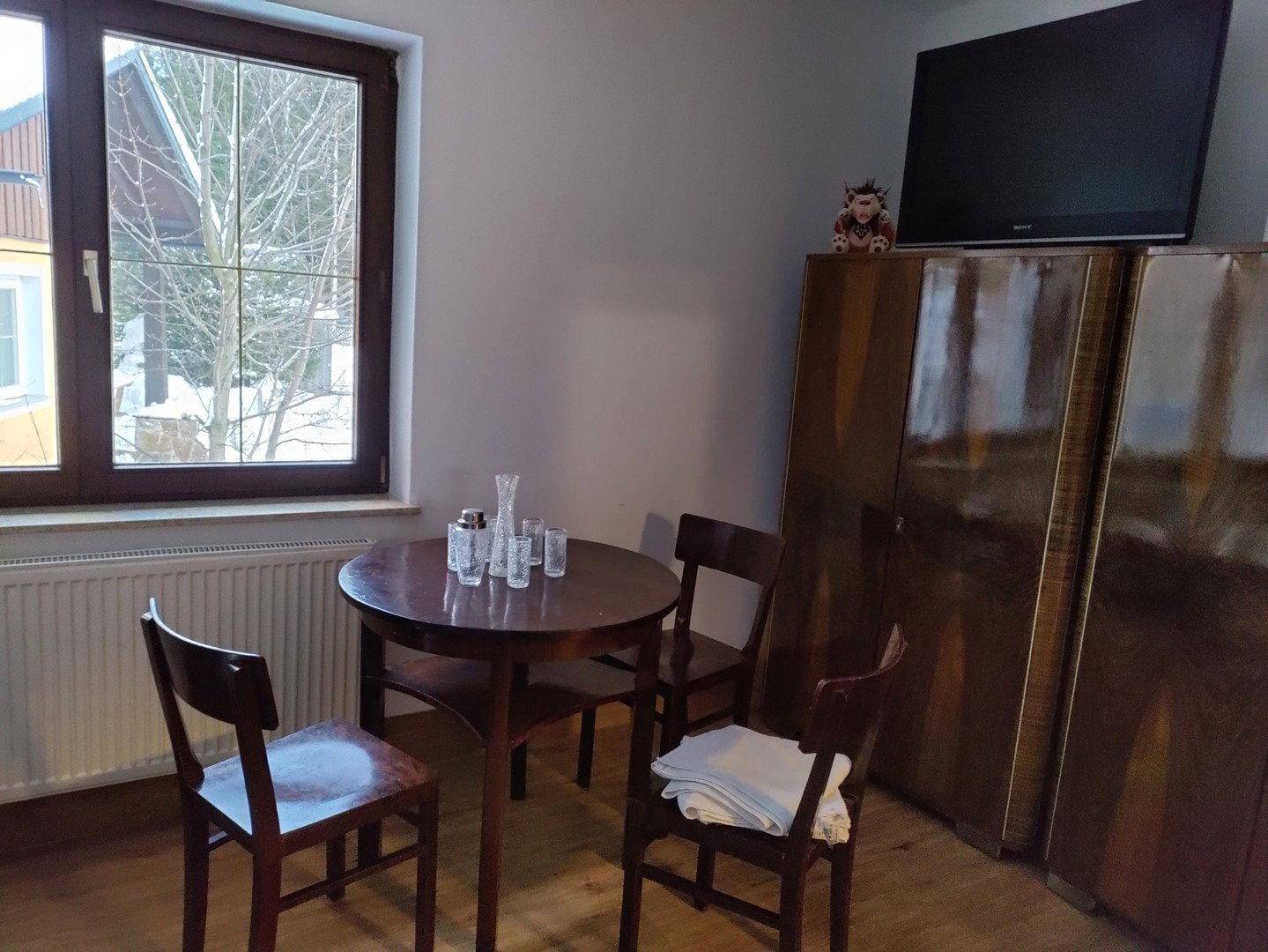 Schlafzimmer mit Esstisch, Stühlen, Vintage-Kleiderschränken und einem Fenster mit Blick nach draußen.