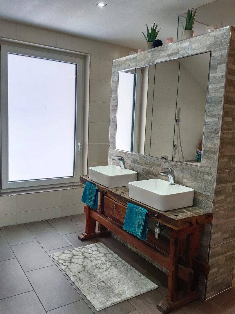 Modernes Badezimmer mit Doppelwaschbecken auf Holzunterschrank und großem Spiegel.