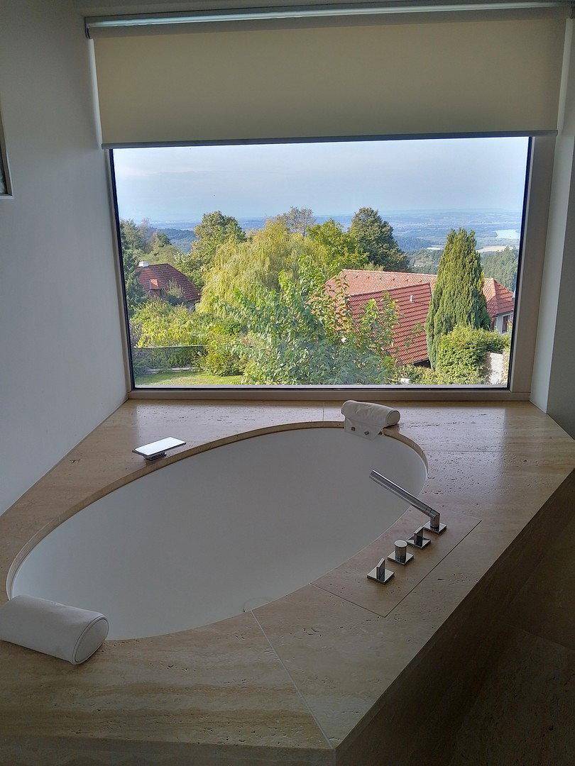 Luxuriöse Eckbadewanne mit Panoramablick durch ein großes Fenster auf die umliegende Landschaft.