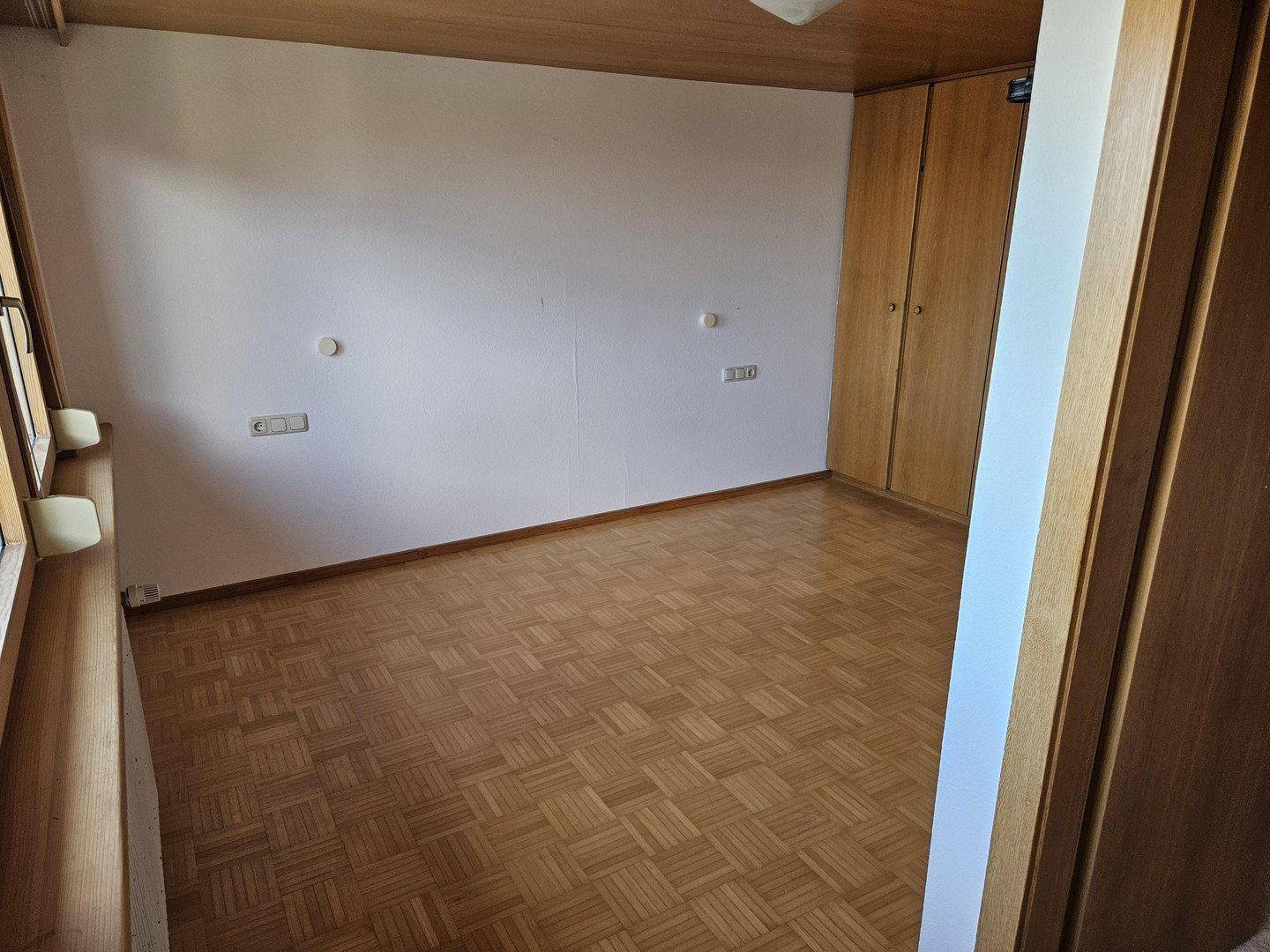 Schlafzimmer mit Parkettboden, Holzdecke und praktischen Einbauschränken.