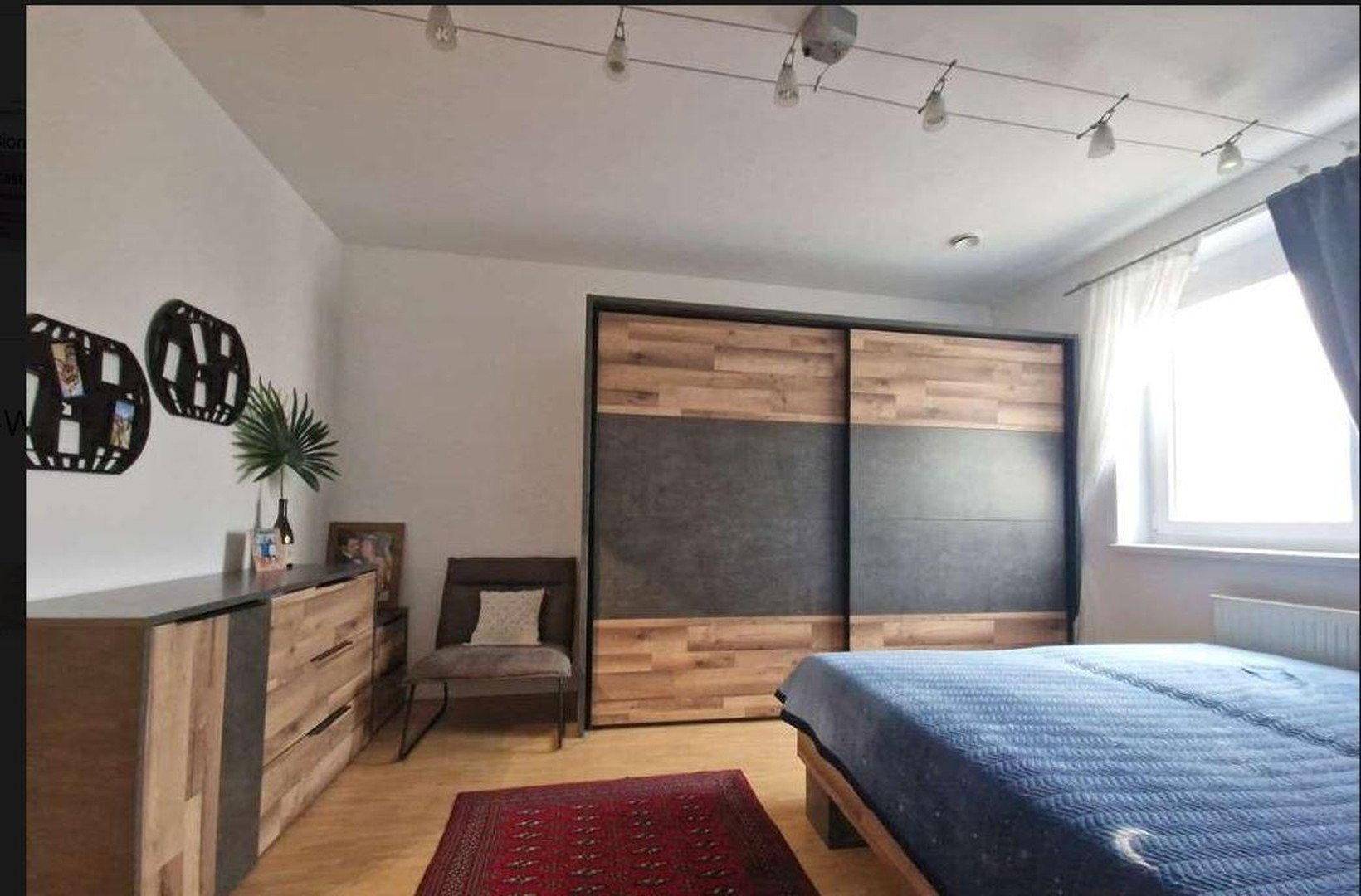 Modernes Schlafzimmer mit großem Kleiderschrank, Doppelbett und Holzboden.