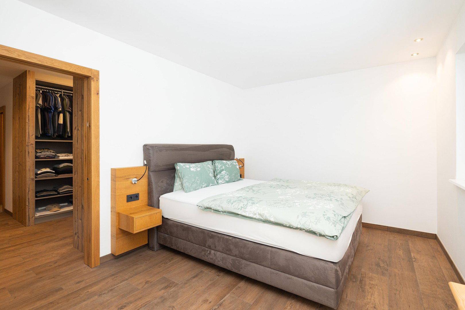 Schlafzimmer mit bequemen Doppelbett und direktem Zugang zu einem begehbaren Kleiderschrank.