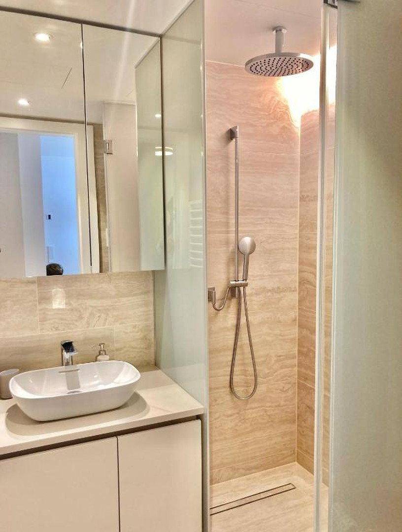 Modernes Badezimmer mit begehbarer Dusche, Regendusche und stilvollem Waschbecken.