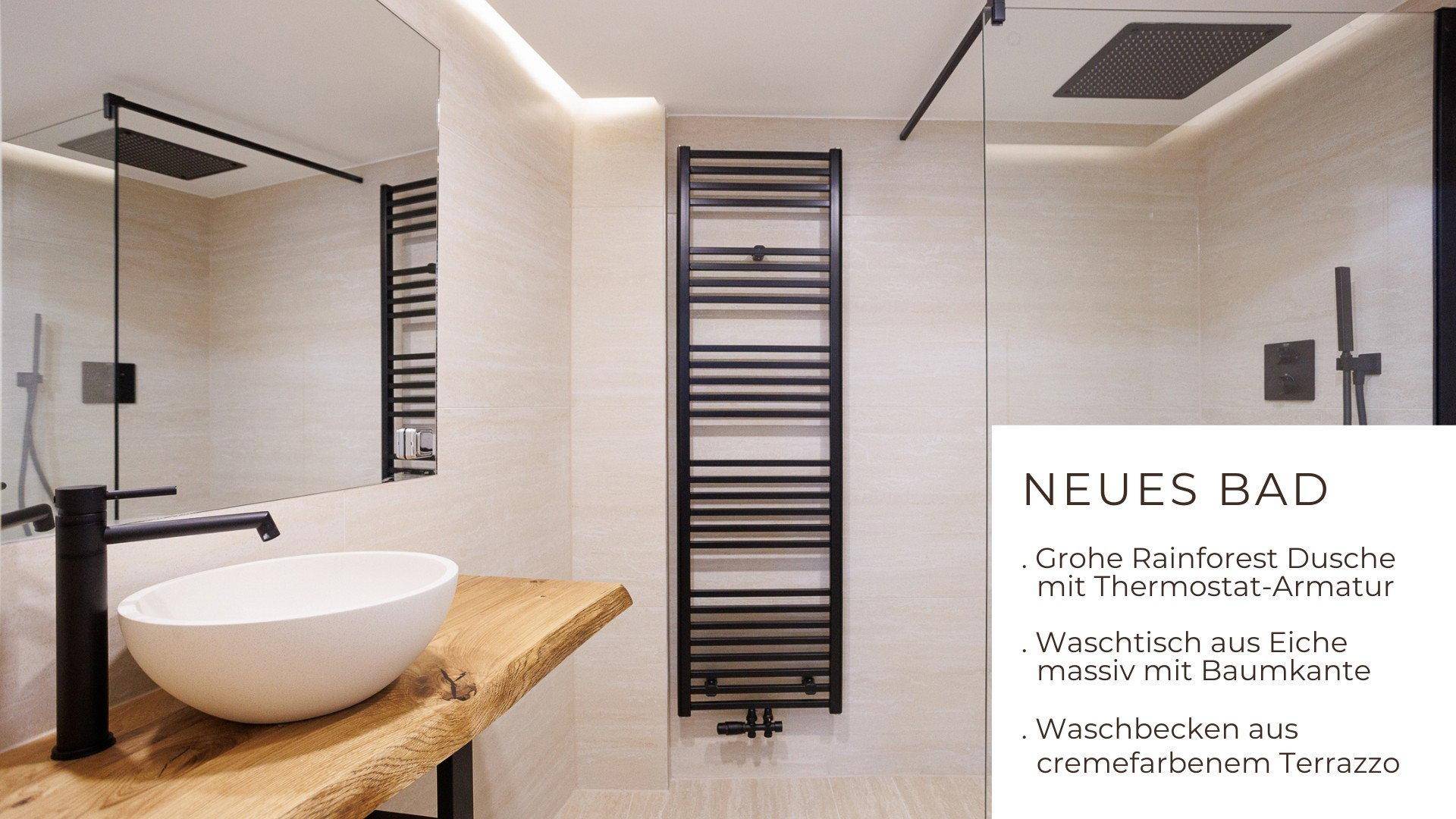 Elegantes Badezimmer mit großer Regendusche, beheiztem Handtuchhalter und Waschtisch aus Eichenholz.