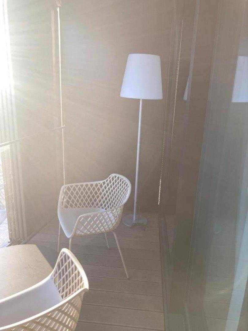 Heller Balkon mit Holzfußboden, modernen Outdoor-Möbeln und viel Sonnenlicht.