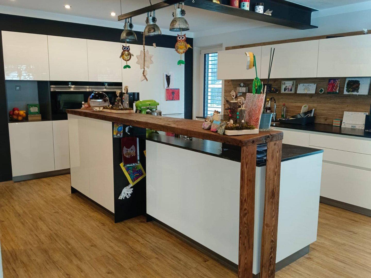 Moderne Küche mit weißen Hochglanzfronten, Kücheninsel und Holzakzenten.