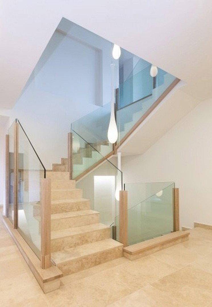 Elegante Treppe mit Natursteinstufen, Glasgeländer und modernen Hängeleuchten.