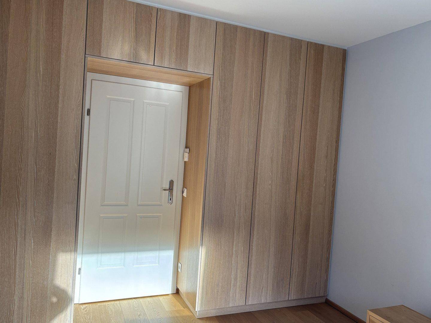 Schlafzimmer mit raumhohen Holz-Einbauschränken und hellem Holzboden.