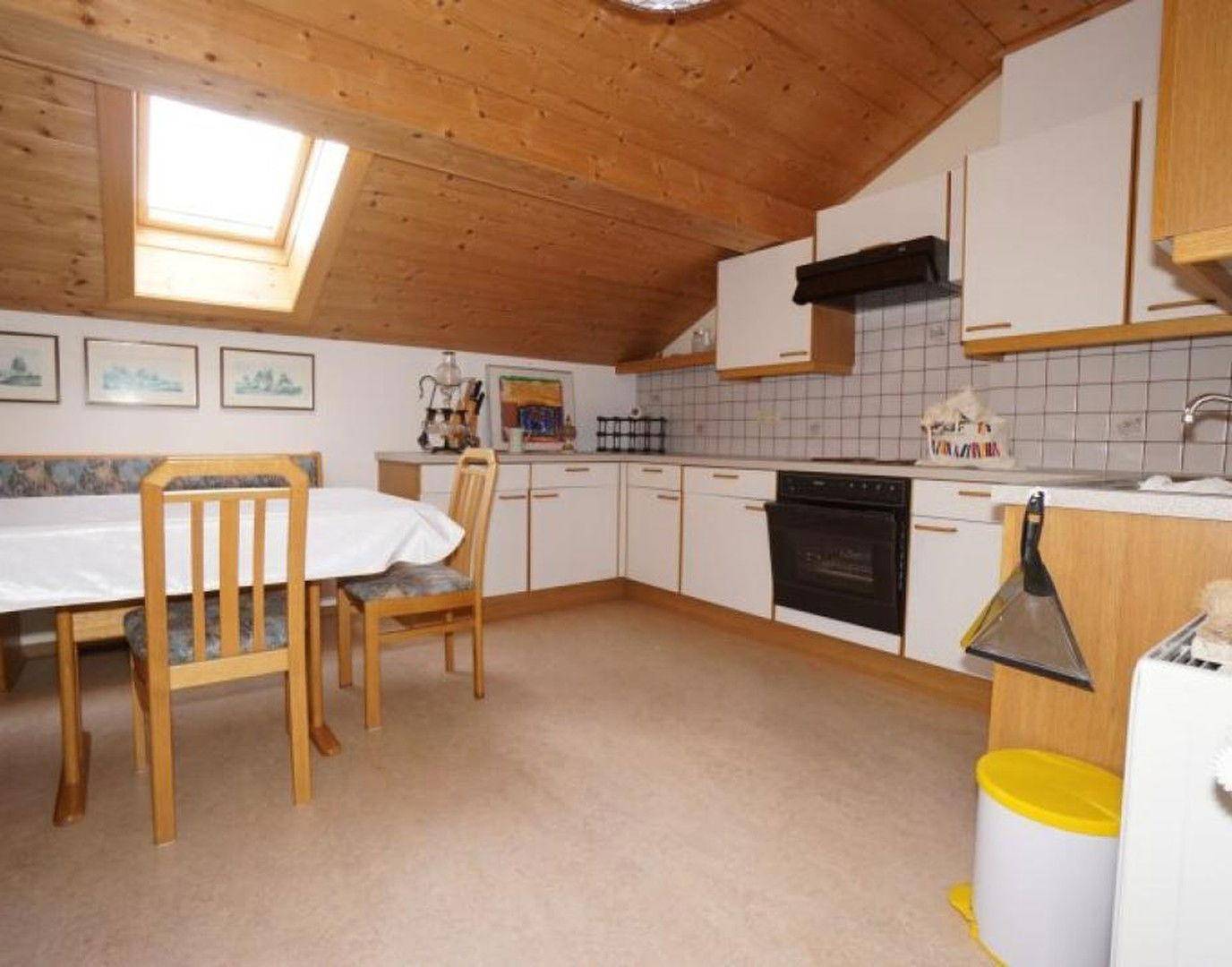 Helle Dachgeschossküche mit Einbauküche, Essbereich und Dachfenster für natürliches Licht.