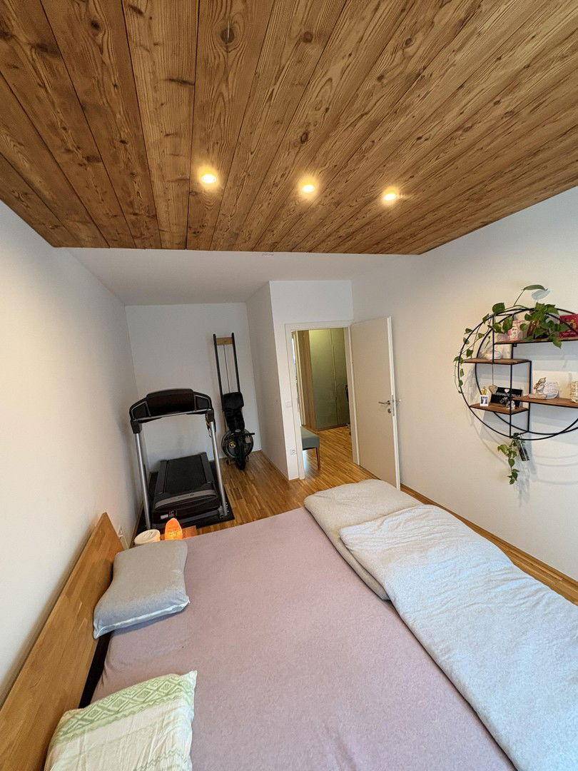 Schlafzimmer mit Holzboden, Holzakzentdecke und einem Laufband für sportliche Aktivitäten.