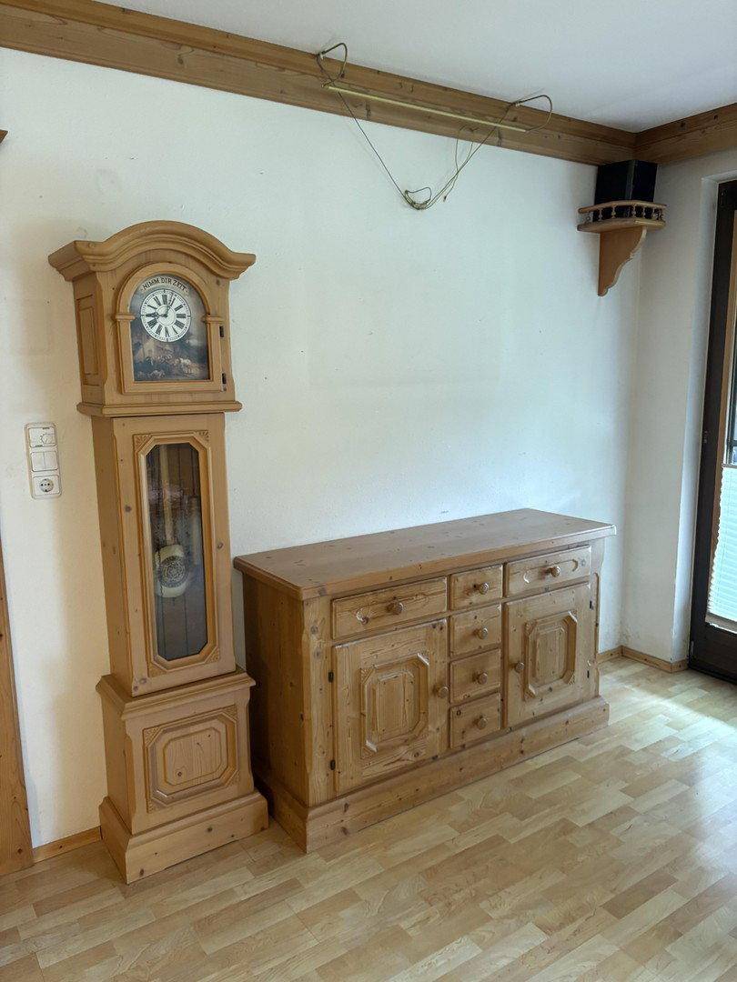 Flur oder Wohnbereich mit einer Standuhr und einem traditionellen Holzschrank auf Laminatboden.