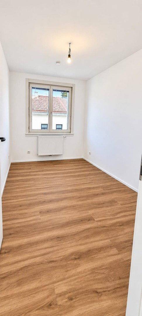 Gemütliches Schlafzimmer mit Laminatboden und einem Fenster, das für ausreichend Tageslicht sorgt.