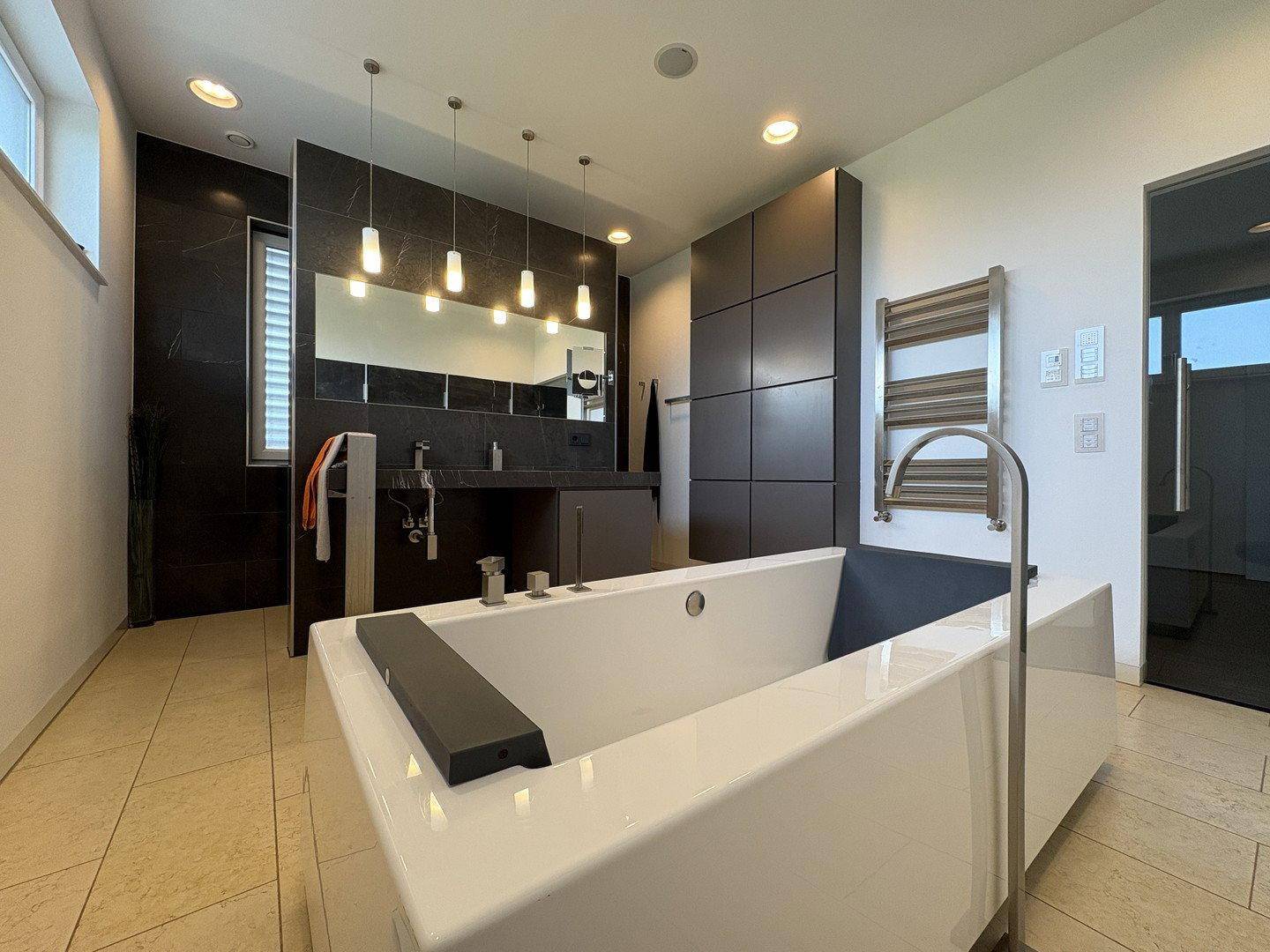 Modernes Badezimmer mit freistehender Badewanne, Doppelwaschbecken und beheiztem Handtuchhalter.