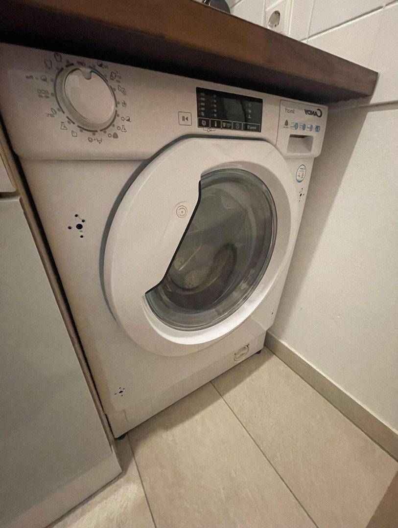 Nahaufnahme einer integrierten Waschmaschine unter einer Holzarbeitsplatte in der Küche.