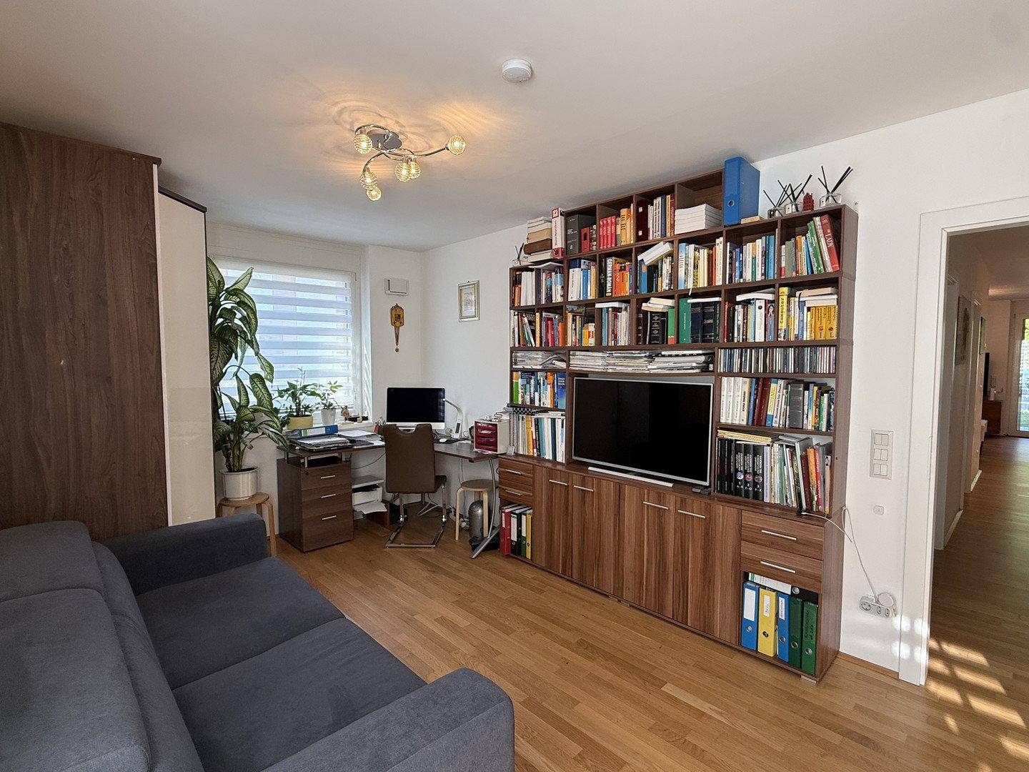 Geräumiges Arbeitszimmer mit großem Bücherregal, Schreibtisch und Sofa, ideal für Home-Office.