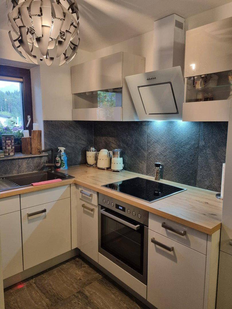 Moderne Küche mit Induktionskochfeld, Backofen und hellen Holz-Arbeitsplatten.