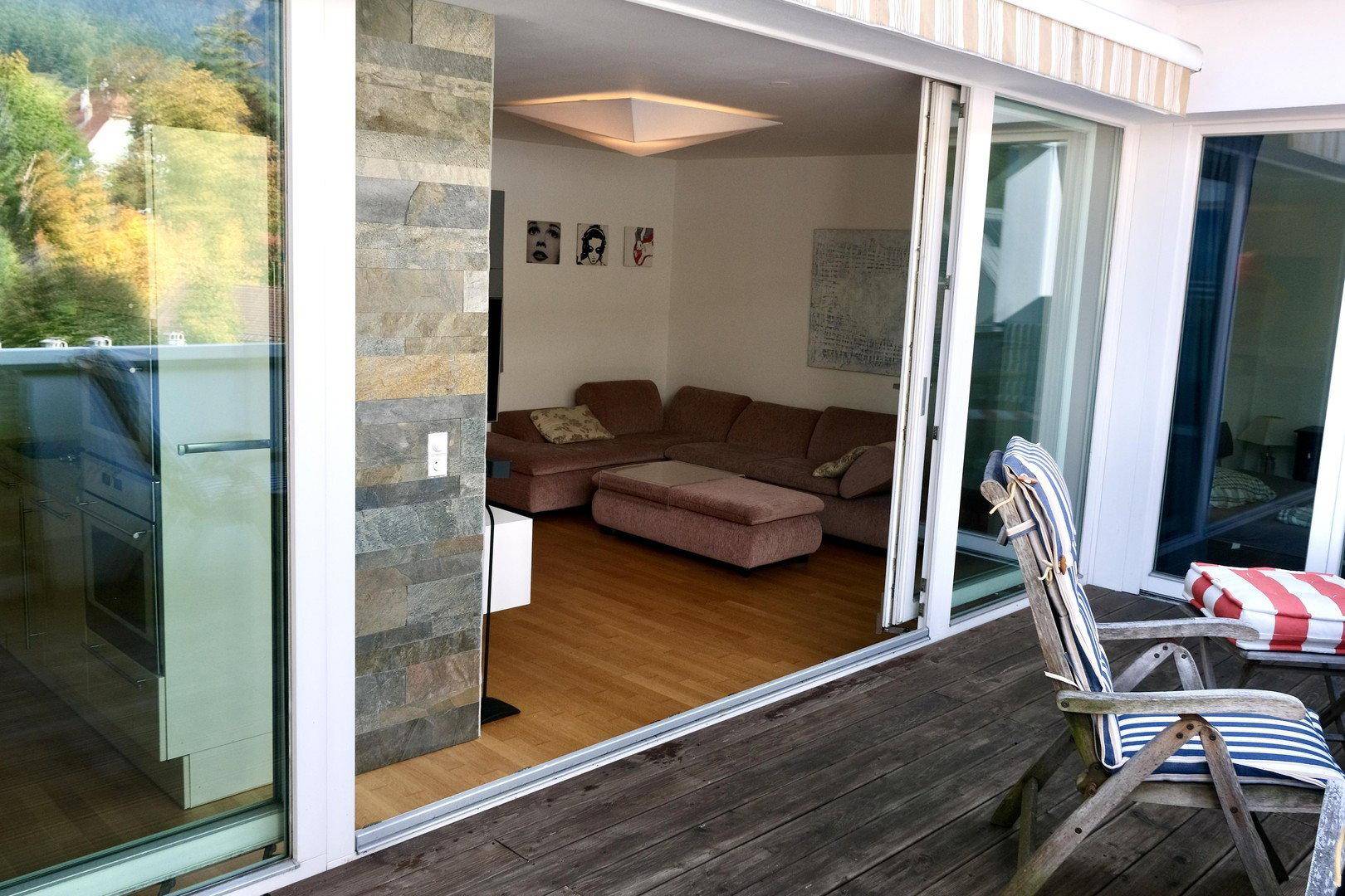 Helles Wohnzimmer mit Holzboden und direktem Zugang zur möblierten Terrasse.