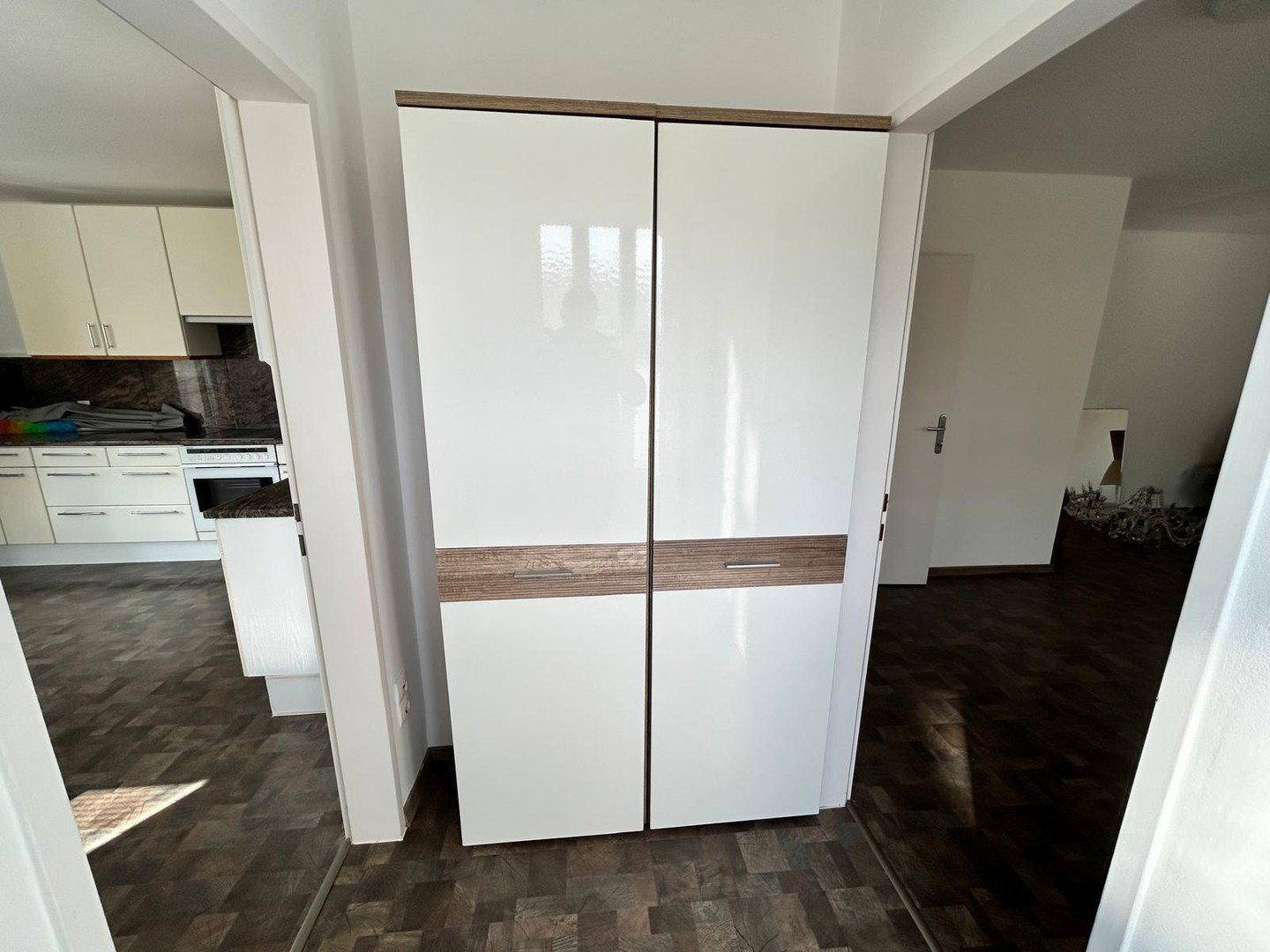 Heller Flurbereich mit modernem Schrank und dunklem Fliesenboden, der zur Küche führt.