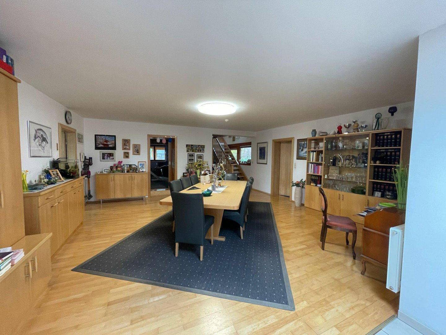 Geräumiger Essbereich mit Holzboden, großem Esstisch und Vitrinen für Geschirr.