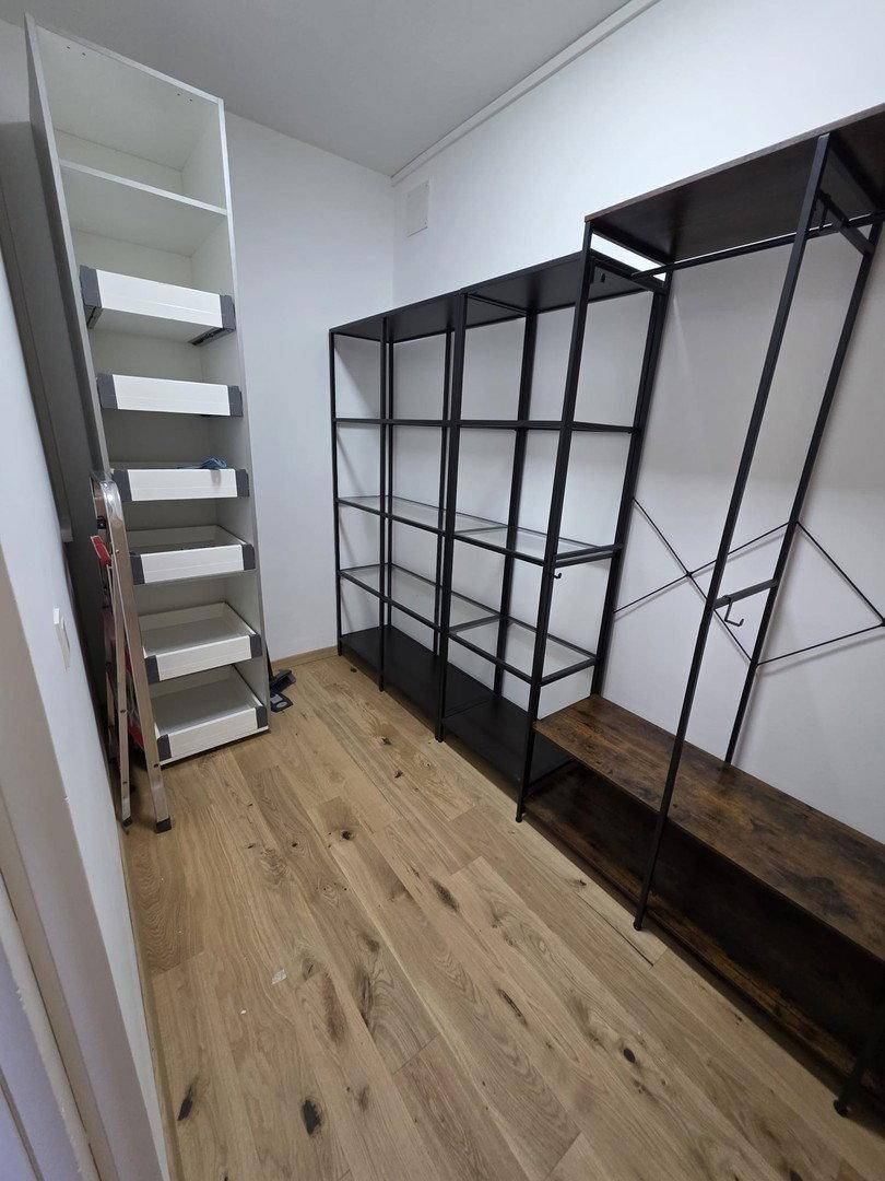 Geräumiger begehbarer Kleiderschrank mit offenen Regalsystemen und Holzfußboden.