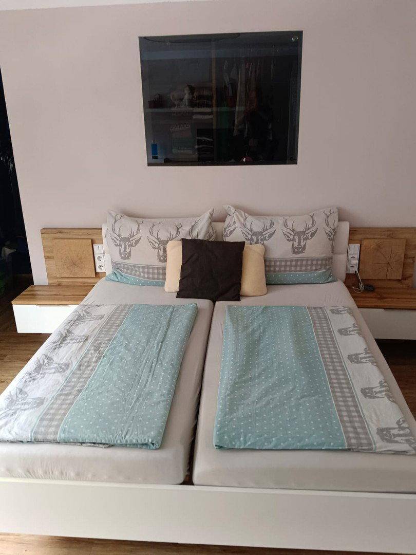 Gemütliches Schlafzimmer mit Doppelbett, Holz-Nachttischen und alpinen Dekokissen.