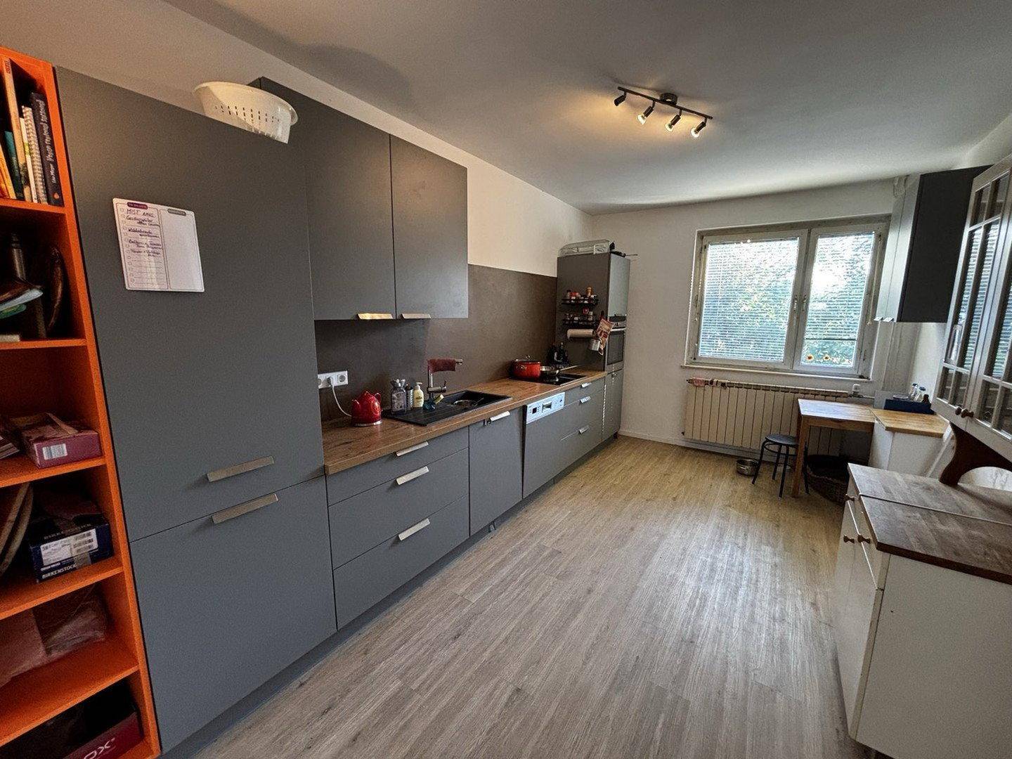 Funktionale Küche mit grauen Schränken, Fenster und ausreichend Arbeitsfläche.