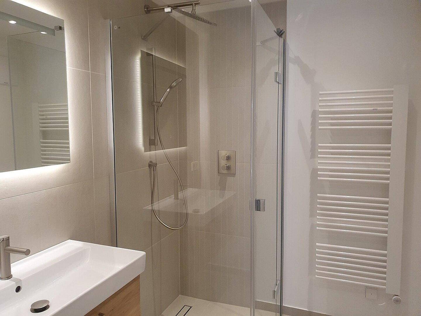 Modernes Badezimmer mit begehbarer Dusche, Einzelwaschbecken und beheiztem Handtuchhalter.