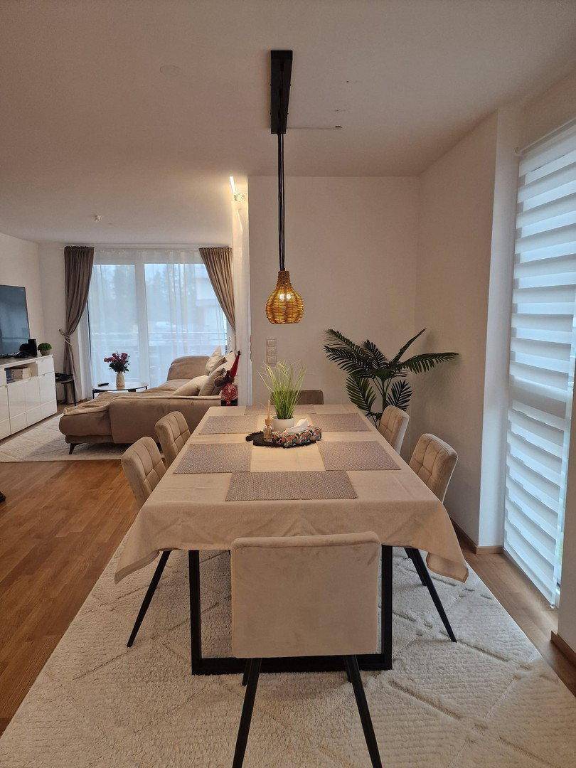 Heller Essbereich mit modernem Tisch und Stühlen, offen zum gemütlichen Wohnzimmer.