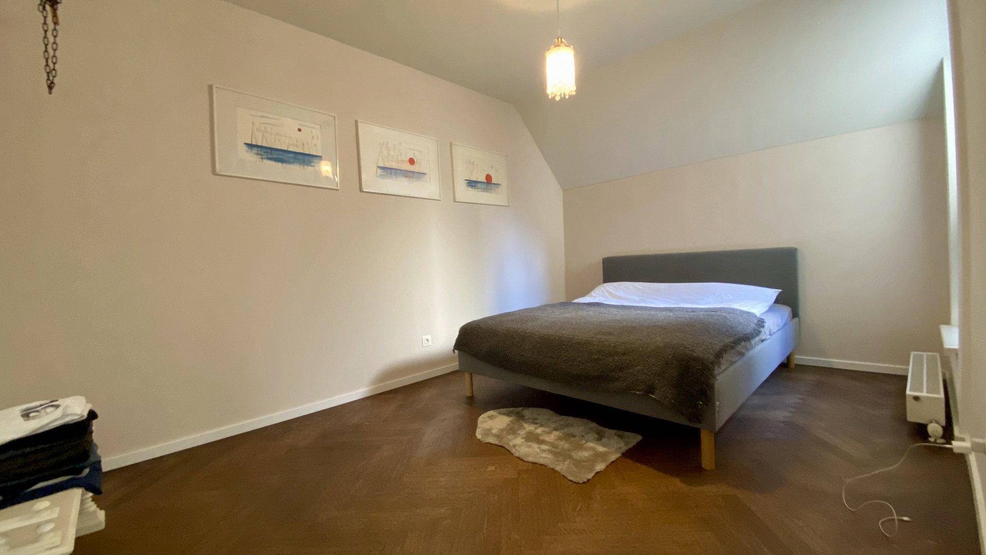 Ruhiges Schlafzimmer mit Holzboden, Doppelbett und schlichter Wanddekoration.