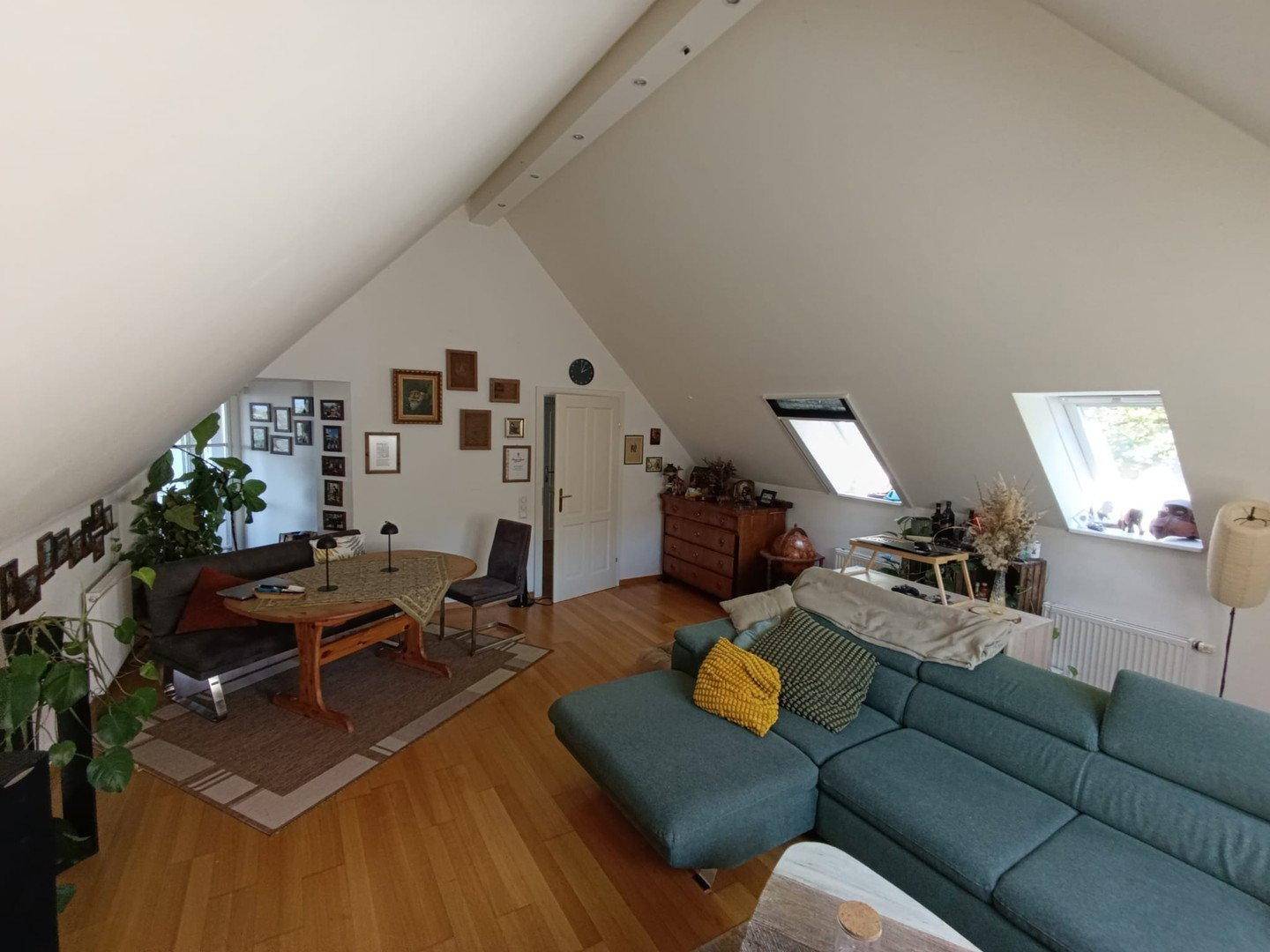 Geräumiger Wohn-Essbereich im Dachgeschoss mit Holzboden, Dachfenstern und gemütlicher Sitzecke.