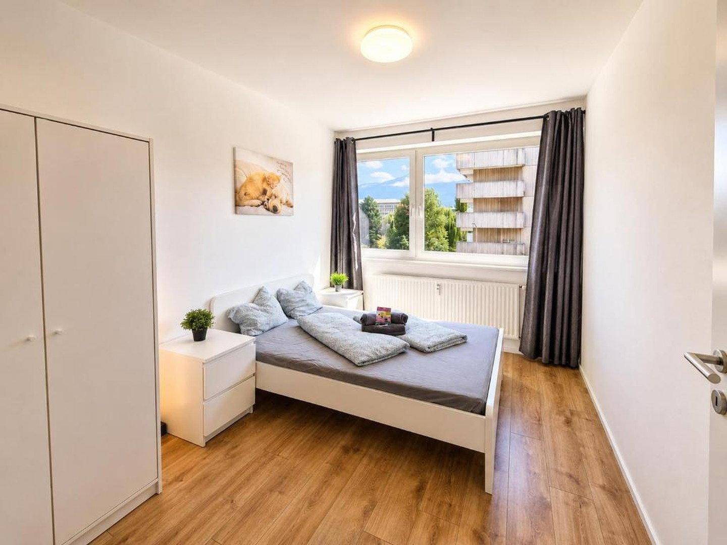 Schlafzimmer mit Doppelbett, Kleiderschrank und Fenster, das einen Blick auf die Umgebung bietet.