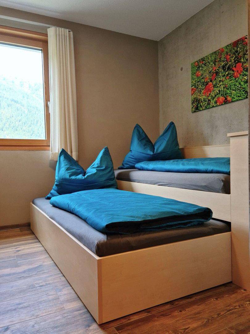Kinderzimmer mit Etagenbetten, Holzboden und Fenster mit Blick auf die grüne Landschaft.