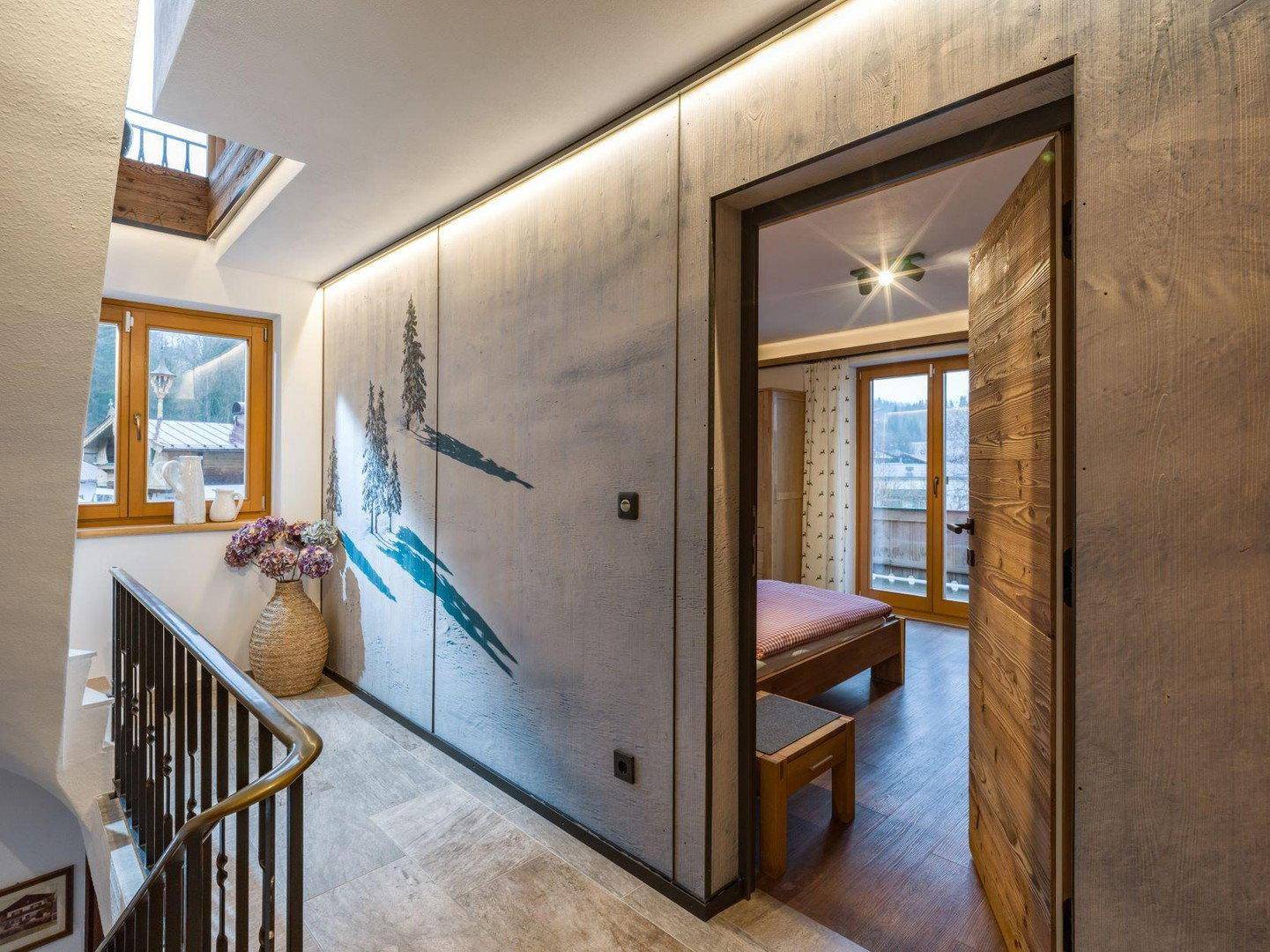 Heller Flur mit Treppe, dekorativer Wandgestaltung und Zugang zu den Schlafzimmern.