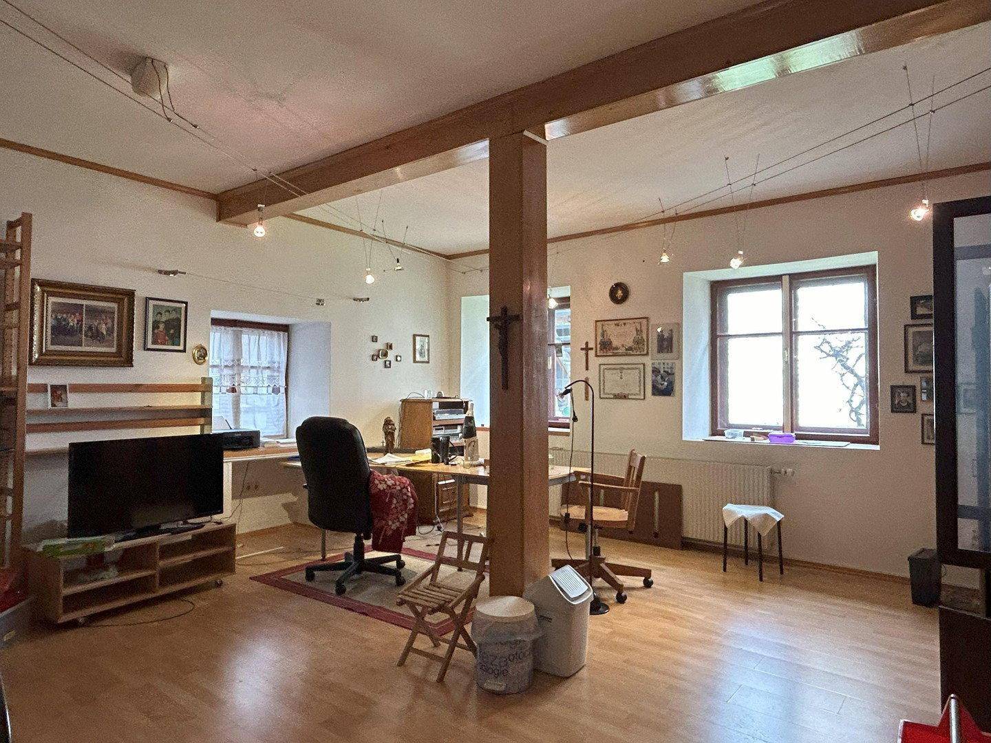 Geräumiges Büro mit Holzbalken, mehreren Fenstern und Arbeitsbereich, ideal für Home-Office.