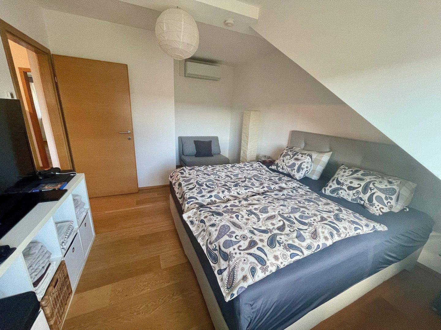 Schlafzimmer mit Doppelbett, Holzboden und Klimaanlage, ideal für angenehme Temperaturen.