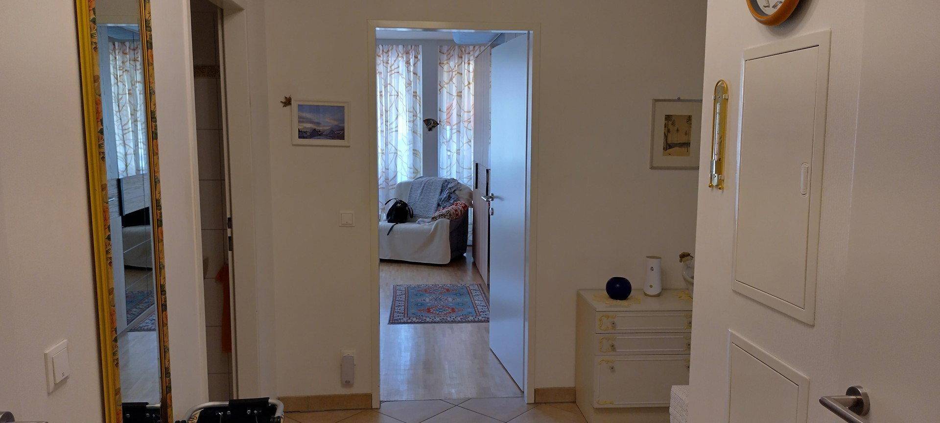 Flur mit Zugang zu einem weiteren Zimmer, gekennzeichnet durch einen Fliesenboden.