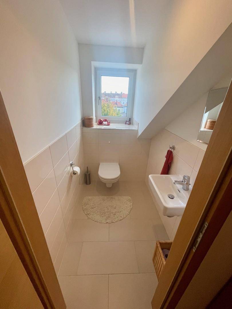 Helles Gäste-WC mit Fenster, modernen Fliesen und Dachschräge im oberen Stockwerk.