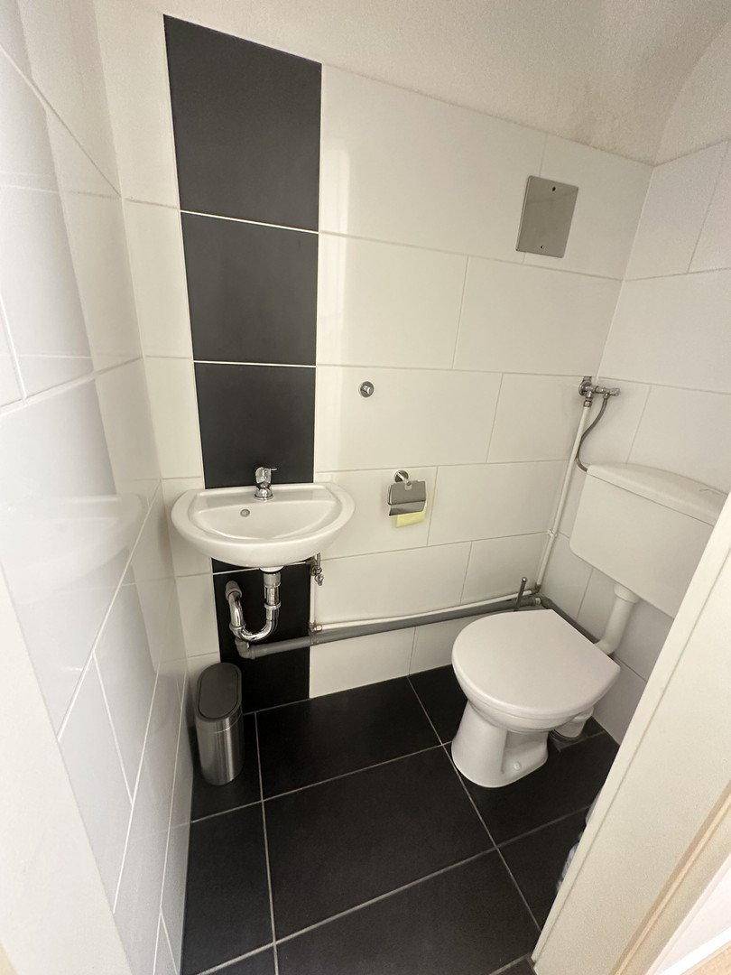 Kleines Gäste-WC mit Waschbecken, Toilette und kontrastreichen schwarz-weißen Fliesen.