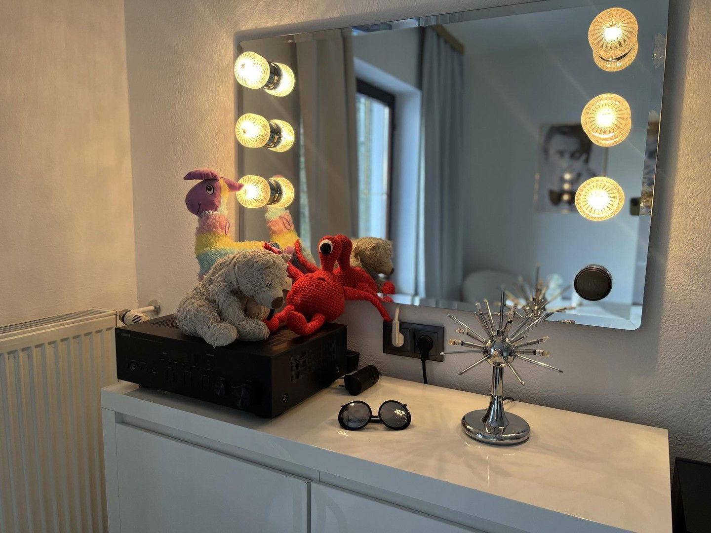 Schminktisch mit beleuchtetem Spiegel und dekorativen Elementen in einem Schlafzimmer.