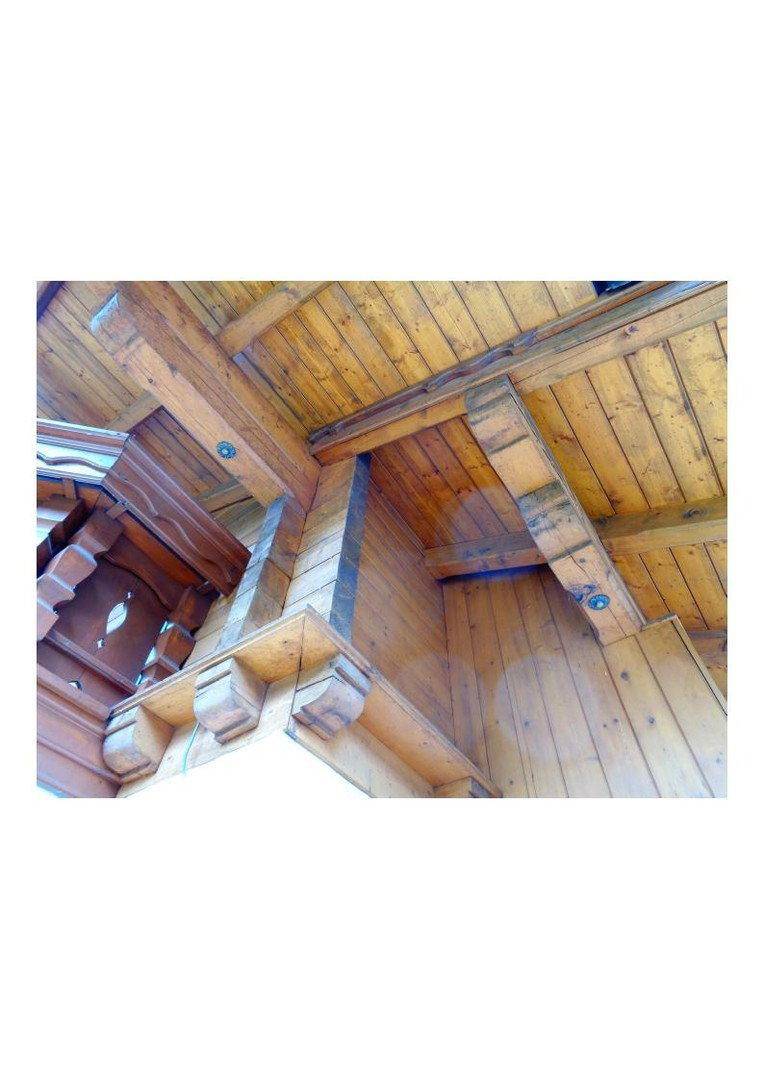 Detailansicht eines traditionellen Holzbalkons mit aufwendigen Schnitzereien und Holzdecke.