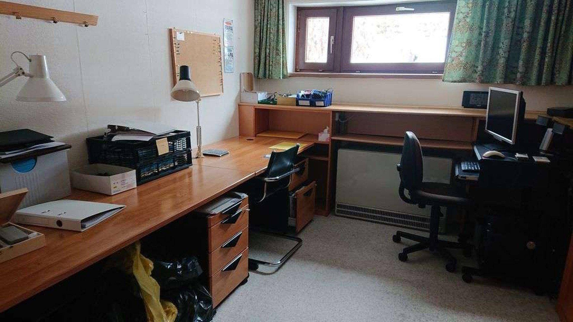 Arbeitszimmer mit Schreibtisch, Bürostuhl und Fenster mit Blick ins Grüne.